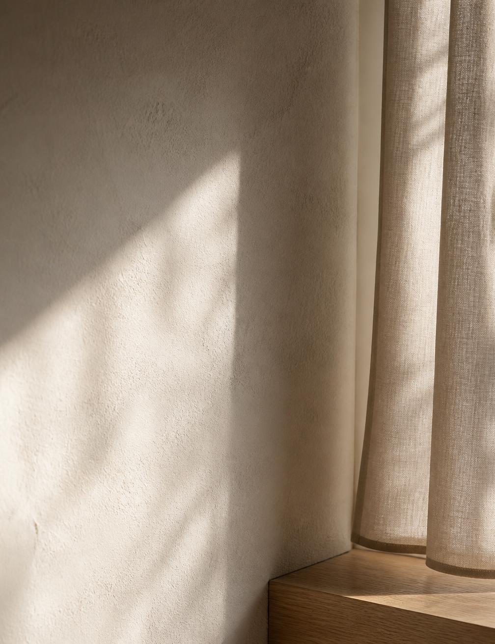 Detalhe de parede texturizada com luz rasante e cortina de linho